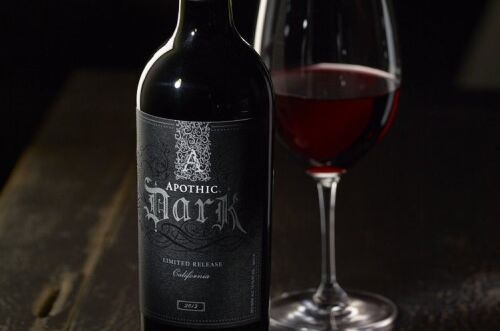 Flasche Apothic Dark Rotwein neben Glas auf dunklem Tisch, zeigt intensive rubinrote Farbe, perfekte Wahl für kraftvolle Rotweine.