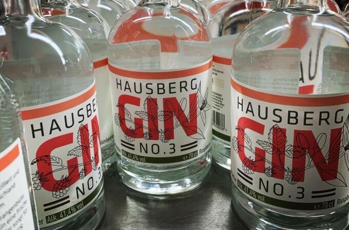 Mehrere Flaschen Hausberg Gin No.3 mit 41.4% Alkoholgehalt, auf einem Tisch arrangiert, bereit für den Verkauf.