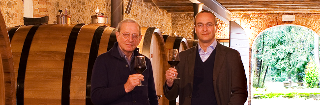 Fernando Roberto Pighin mit Glas Wein in Weinkellerei mit großen Holzfässern, genießend im gemütlichen Ambiente