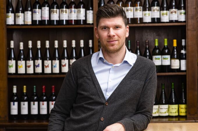 Matthias Hummel vor einem Weinregal mit verschiedenen Weinflaschen. Entdecken Sie die exquisite Auswahl an Lieblingsweinen mit Matthias Hummel!