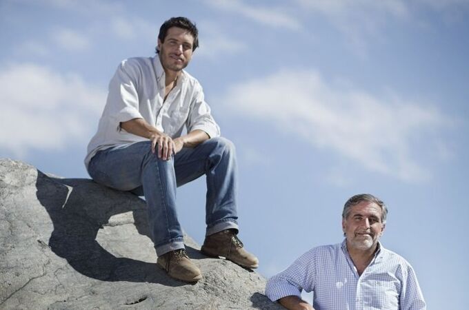 Sebastian Zuccardi und Jose Zuccardi stehen auf einem Felsen in einem argentinischen Weinberg unter blauem Himmel.