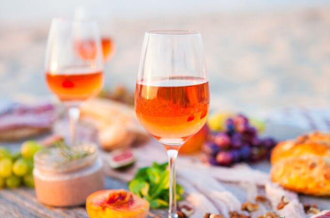 Orange Wine in schönen Weingläsern auf einem rustikalen Tisch mit Obst, Brot und Wurstwaren. Perfekte Sommerbegleitung!