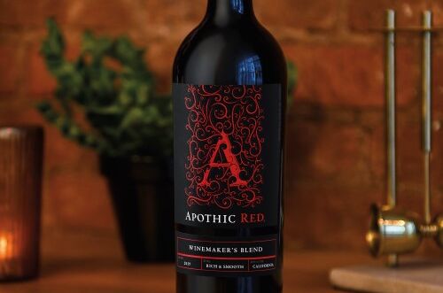 Eine Flasche Apothic Red Winemaker's Blend Rotwein, elegant vor Backsteinmauer und Kerzenlicht präsentiert – ideales Geschenk!