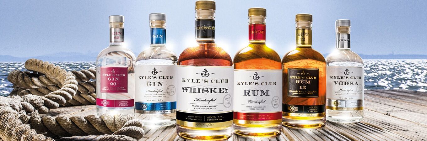 Kyle's Club Spirituosen Gin 23, Gin, Whiskey, Rum, Rum 12 und Vodka auf einem Holzsteg am Wasser im Sonnenschein.