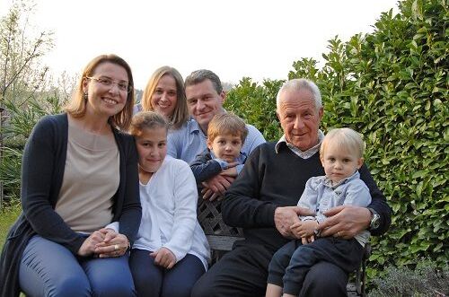 Familienfoto der Familie Mazzei von Alibrianza, sitzend im Garten, mit entspannten lächelnden Mitgliedern. Genießen Sie die Tradition italienischer Weine!