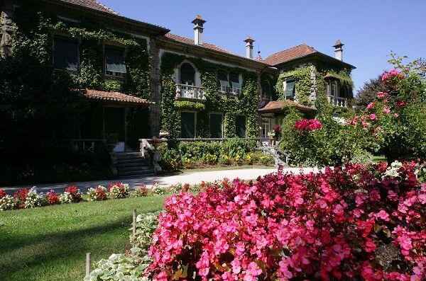 Das historische Haupthaus der Quinta da Aveleda in Portugal, umgeben von üppigen Gärten und blühenden Blumenbeeten – ein malerischer Ort für Weinliebhaber!