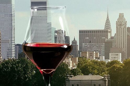 Rotes Weinglas vor der Skyline einer US-amerikanischen Stadt, perfekt für Liebhaber von amerikanischen Rotweinen, Qualitätswein aus den USA.