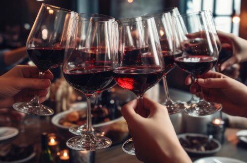 Gruppe von Menschen stößt mit Gläsern französischen Rotwein an, in gemütlicher Atmosphäre eines Restaurants. Genießen Sie edlen französischen Rotwein!