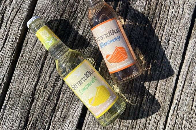 Strandgut Fruchtbrise Zwei Flaschen Strandgut Fruchtbrise auf Holzuntergrund – Sorten Limoncello und Bitterorange, aromatisierte weinhaltige Cocktails mit fruchtigem Geschmack und spritzigem Charakter.