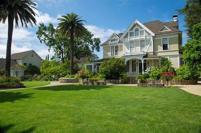 Elegante Sutter Home Tasting Room Inn mit üppiger Landschaft, Palmen und blühenden Gärten, idealer Ort für Weinproben und Hochzeiten.