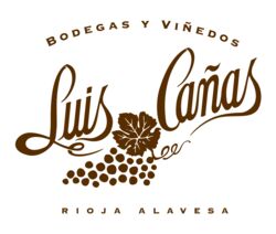 Das Logo der Bodegas y Viñedos Luis Cañas zeigt braune Schrift, eine Traube und ein Blatt auf weißem Hintergrund. Ideal für Weinliebhaber.