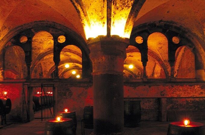 Historischer Weinkeller des Kloster Eberbach mit beleuchteten Weinfässern und romanischen Bögen, ideal für Weinverkostungen.