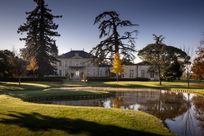 Das Château Cheval Blanc in Frankreich, umgeben von gepflegtem Rasen und Teich im Vordergrund. Eine historische Weingüter-Atmosphäre!