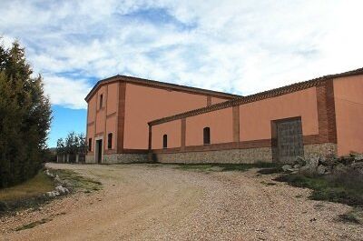 Foto der Bodega Pinord in Spanien, eines traditionellen Weinguts mit rosaner Fassade und türkisfarbenem Himmel.