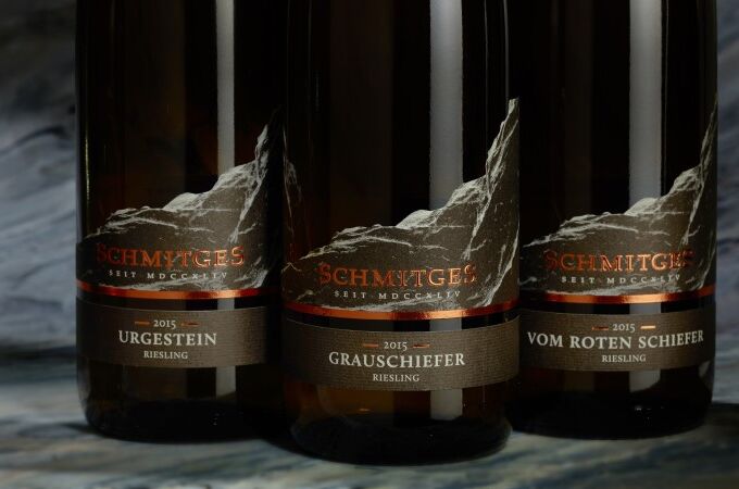 Fünf Flaschen Schmitges Riesling (Treppchen, Urgestein, Grauschiefer, Vom Roten Schiefer, Treppchen Auslese) vor unscharfem Hintergrund.