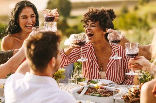 Freunde stoßen mit Rotwein während eines Essens im Freien an. Genießen Sie australischen Wein in guter Gesellschaft.