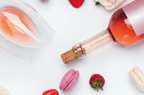 Flasche Roséwein mit Glas, Erdbeeren und Macarons. Perfektes Probierpaket für fruchtigen Genuss!