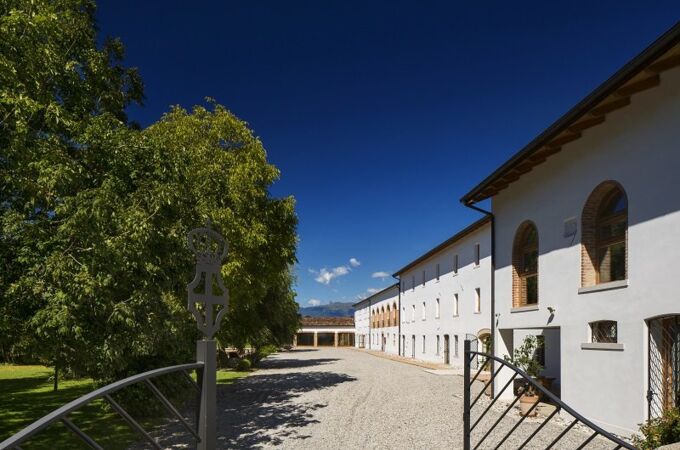 Das Weingut Bottega Villa Rosina mit weißer Fassade, grüner Umgebung und sonnigem Himmel in Italien. Entdecken Sie Feinweine und Spirituosen!