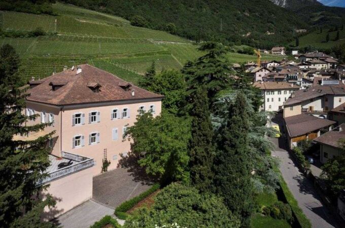 Luftaufnahme eines Weinguts von Wilhelm Walch in Südtirol, Italien, umgeben von Weinbergen und einem malerischen Dorf