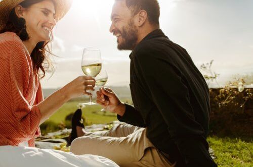 Zwei Personen genießen bei Sonnenschein ein Glas Weinschorle im Freien. Perfekte Erfrischung für warme Tage!