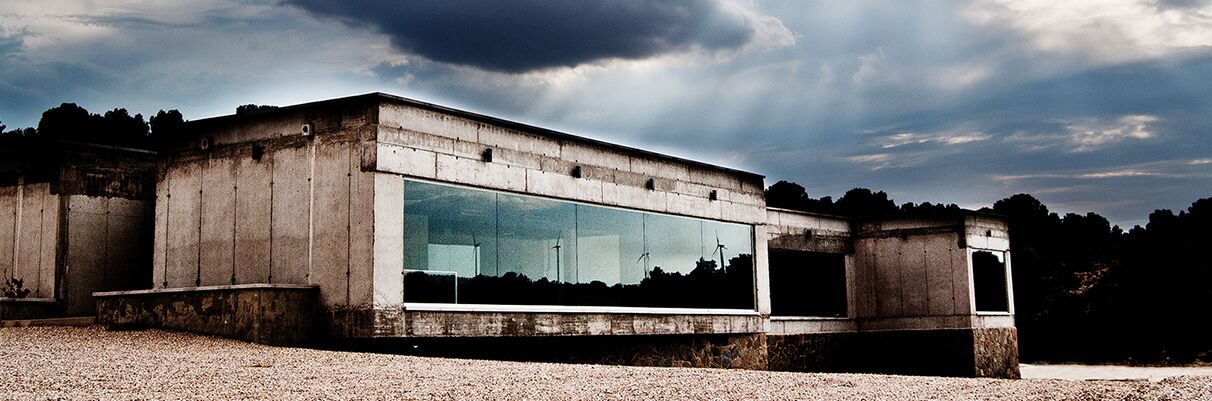 Modernes Weingut Ego Bodegas in Spanien mit großem verglasten Gebäudekomplex und dramatischem Himmel im Hintergrund.