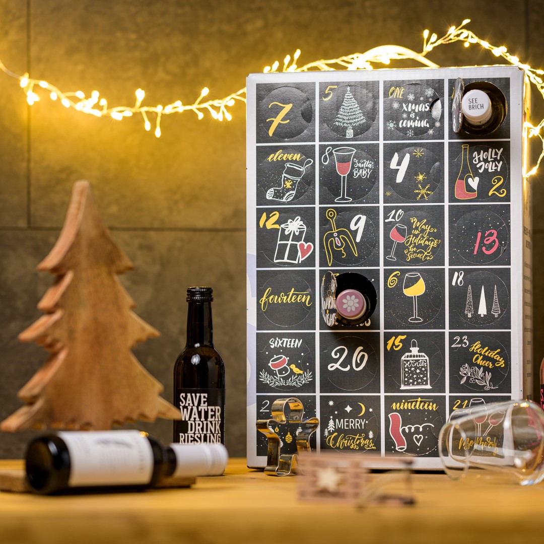 Weinadventskalender von Schneekloth mit 24 Weinüberraschungen, schwarz-goldenes Design, Weihnachtsumgebung, ideal für Weinliebhaber.